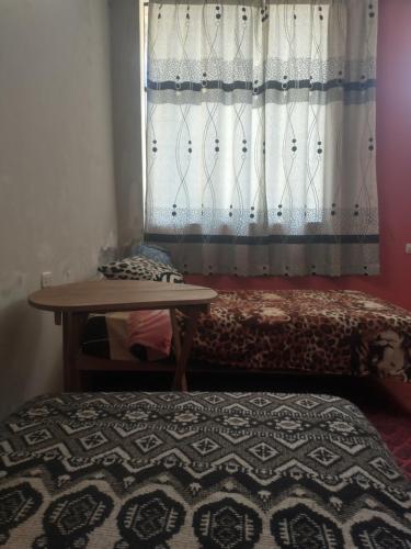 a bedroom with a bed and a table and a window at Hospedaje Akankma in Juliaca