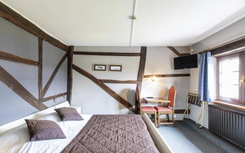 a bedroom with a bed and a table and a window at Le Grandgousier Mirwart in Mirwart