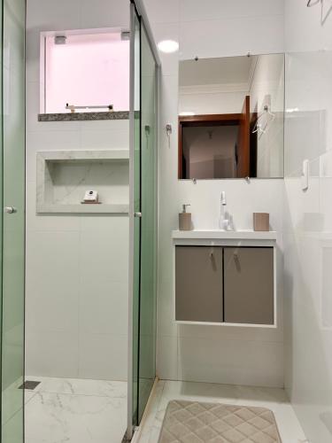uma casa de banho com uma cabina de duche em vidro e um lavatório. em Apto térreo com garagem coberta em Tijucas