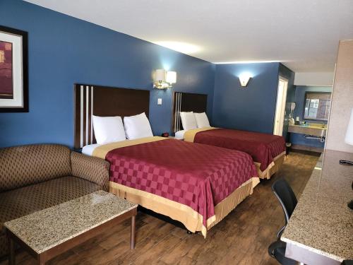 a hotel room with two beds and a couch at Texas Inn and Suites Raymondville in Raymondville