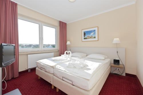 a hotel room with a large white bed and a window at Michels Hanseatic Hotel Norderney in Norderney