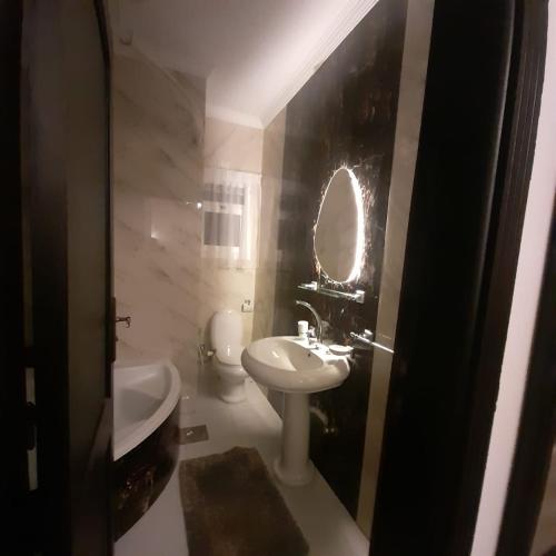 La salle de bains est pourvue d'un lavabo, de toilettes et d'un miroir. dans l'établissement Madinty vg1 مجموعة ٨ فيلا ٤١ مدينتى فرش فندقى بلكامل, à Madinaty