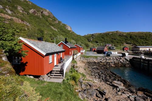 a row of red houses on a hill next to a river at Vesterålen Rorbuer in Bø i Vesterålen