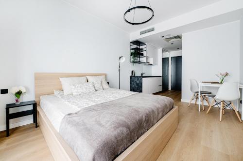 a white bedroom with a large bed and a desk at Chaplin Apartment in Poznań