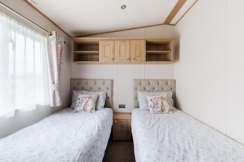 two beds in a small bedroom with a window at Waters Edge, Hoburne Cotswolds in South Cerney