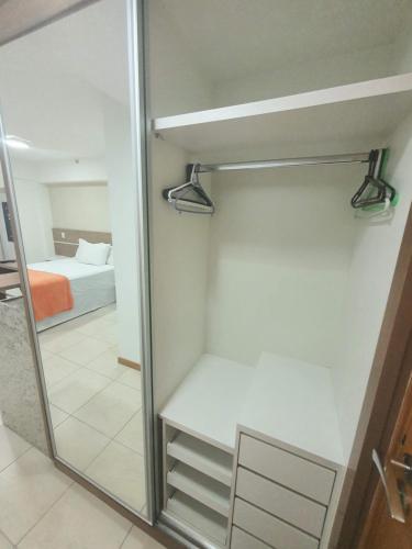 a walk in closet with a mirror and a bed at Flat Saint Moritz Express By Rei dos Flats in Brasilia