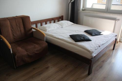 a bed with two pillows sitting next to a chair at Apartment Wielicka Cracow in Krakow