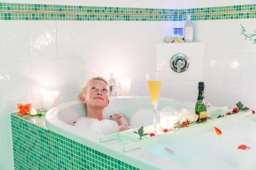 a woman in a bath tub with a glass of champagne at Landhotel zu Heidelberg in Seiffen