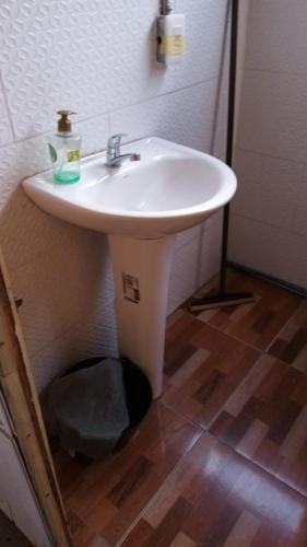 lavabo blanco en un baño con suelo de madera en my bus, en Punta del Diablo