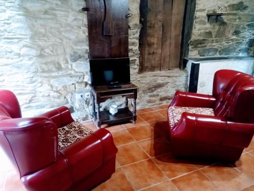 - un salon avec 2 chaises rouges et une télévision dans l'établissement Casa Pacios by M de Santiago, à Tríacastela