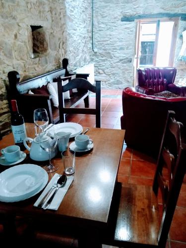 a wooden table with plates and wine glasses on it at Casa Pacios by M de Santiago in Tríacastela