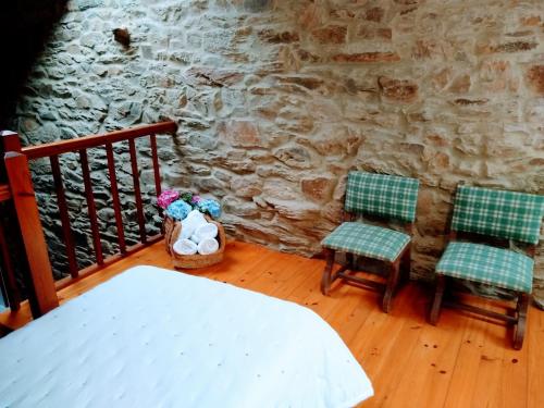 a room with two chairs and a stone wall at Casa Pacios by M de Santiago in Tríacastela