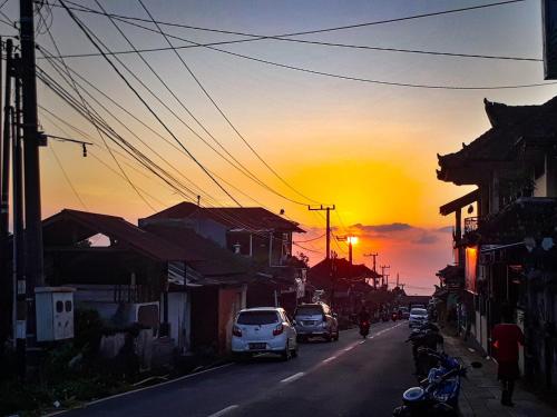 a street with cars driving down a street with a sunset at Keala de Bali in Munduk