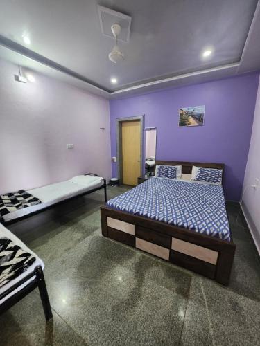 two beds in a room with purple walls at Junglee Nest Holiday Home in Mahabaleshwar