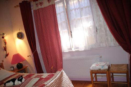 a bedroom with a bed and a window with red curtains at La Maison des Chats in Saint-Mary-le-Plain
