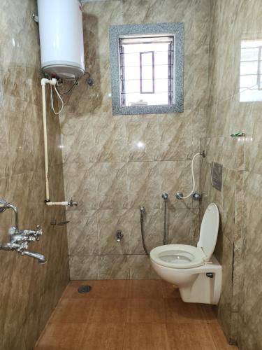 a bathroom with a toilet and a window at Junglee Nest Holiday Home in Mahabaleshwar
