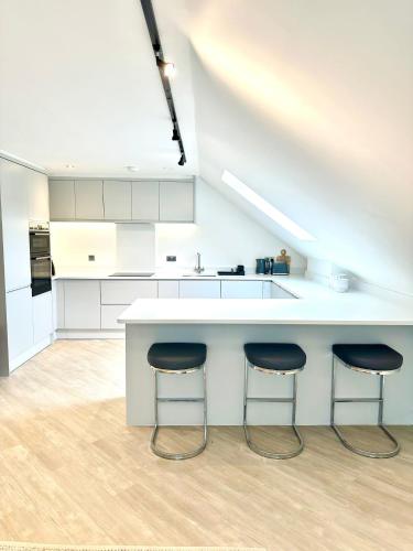 a kitchen with a white counter and two stools at 2 Bedroomed apt by Sefton Park and Spire Hospital in Liverpool