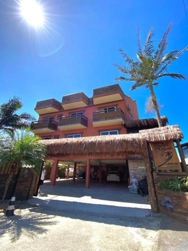 a large building with a palm tree in front of it at Pousada Ondas do Embaú in Palhoça