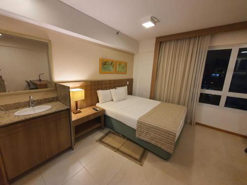 a bedroom with a bed and a bathroom with a sink at Flat Saint Moritz Express By Rei dos Flats in Brasilia