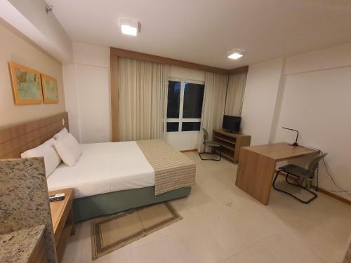 a bedroom with a bed and a desk and a television at Flat Saint Moritz Express By Rei dos Flats in Brasilia