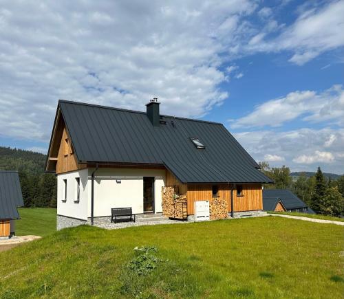 een schuur met een zwart dak op een groen veld bij Chalupa 13ka - Horní apartmán in Smržovka