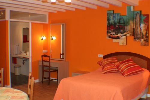 a bedroom with orange walls and a bed with pillows at Logis Hôtel & Restaurant Aux Tauzins in Montfort-en-Chalosse