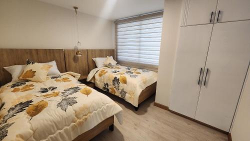 a bedroom with two beds and a white cabinet at 302 Departamento La Terraza in Cuenca