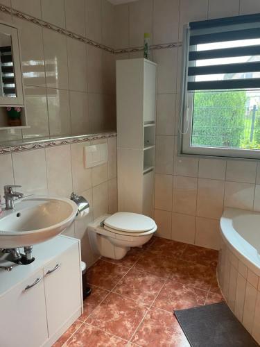 een badkamer met een toilet, een wastafel en een bad bij Ferienhaus in der Stienitzaue in Werneuchen