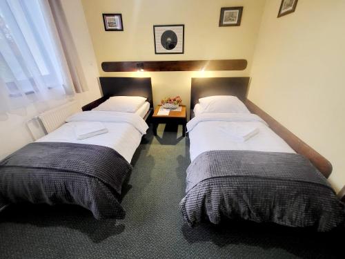 two twin beds in a room with a table at Penzion Bazalka in Jablonec nad Nisou