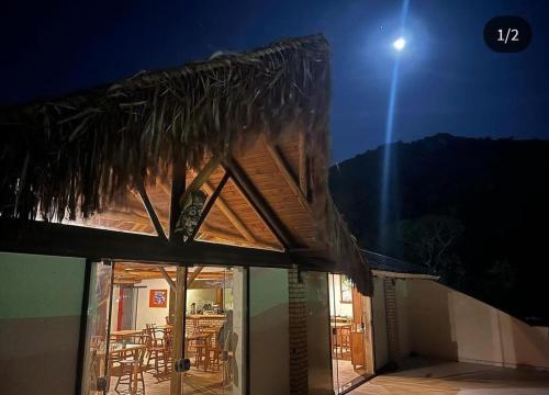 a house with a patio with a straw roof at Pousada Ondas do Embaú in Palhoça