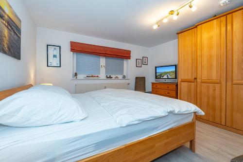 a bedroom with a large white bed and a television at Altstadttor 5 in Westerland