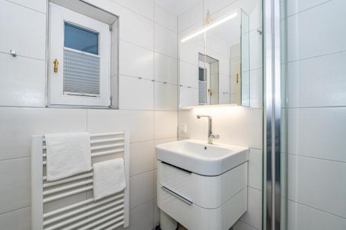 a white bathroom with a sink and a mirror at Altstadttor 5 in Westerland