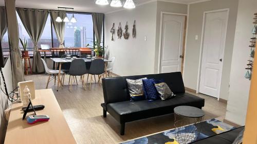 a living room with a black couch and a table at Mesquita Arriendos - Departamento full amoblado para 7 personas in Iquique