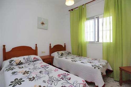 1 dormitorio con 2 camas y una ventana con cortinas verdes en Villa Familiar con piscina privada y Jardin, en Conil de la Frontera