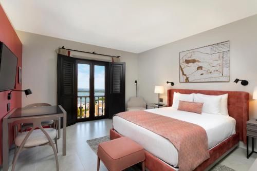 a bedroom with a bed and a desk and a television at Hotel El Convento in San Juan