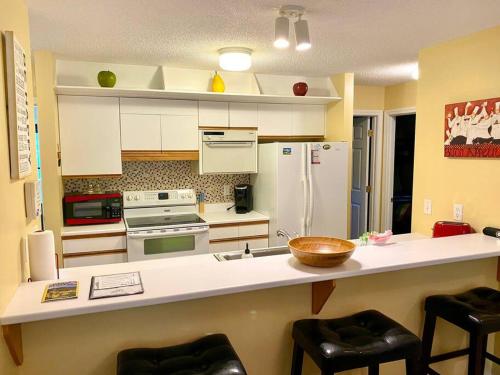 a kitchen with a counter with a refrigerator and stools at Bretton Woods Townhome, Views, 1Gig WiFi, Spacious in Bretton Woods