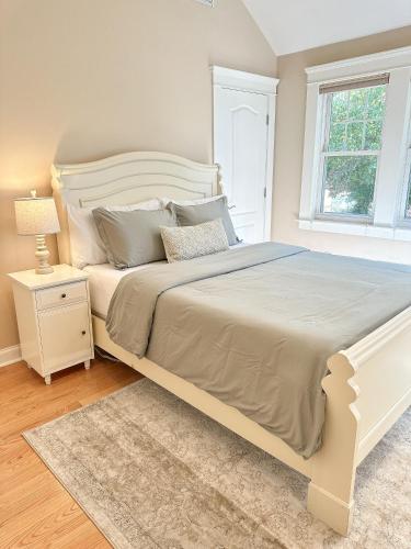 a bedroom with a large white bed and a window at 7 Mins drive to Yale, Large fenced yard in New Haven