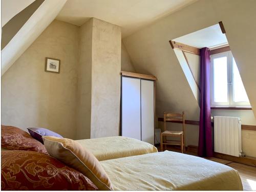 a attic bedroom with two beds and a window at Maison en pierre 4 couchages in Savignac-de-Miremont