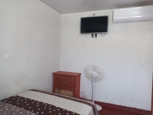 1 dormitorio con 1 cama y TV en la pared en MARANATHA, en El Ñuro