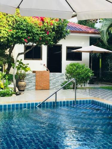 a swimming pool in front of a house at Summer House,shared pool, private bathroom and kitchen in Ban Phlu Yai