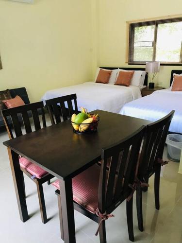 a table and chairs with a bowl of fruit on it at Summer House,shared pool, private bathroom and kitchen in Ban Phlu Yai