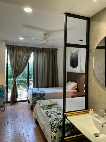 a bedroom with two beds and a mirror and a sink at Hotel Macaw Cúcuta in Cúcuta