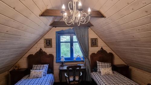 two beds in a attic room with a chandelier at Niezapominajka in Janówek Pierwszy