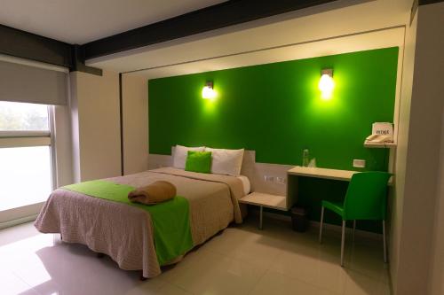a green wall in a bedroom with a bed and a desk at SC HOTEL in Xalapa