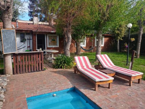 a backyard with two chairs and a swimming pool at Quinta El Cholito in Luján