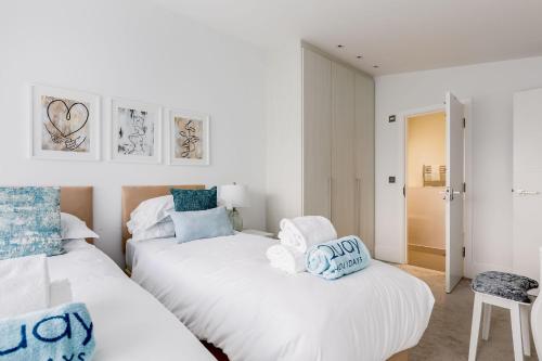 2 Betten in einem Schlafzimmer mit weißen und blauen Kissen in der Unterkunft Windward in Poole