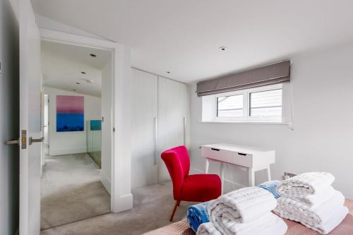 een slaapkamer met een bureau en een rode stoel bij Windward in Poole