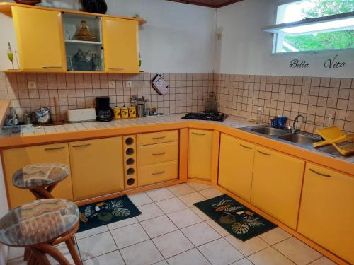 a kitchen with yellow cabinets and a sink at Agréable F2 à Petite-Anse aux Anses d'Arlet MARTINIQUE in Quartier du Fond Fleuri