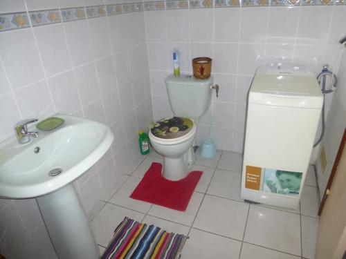 a white bathroom with a toilet and a sink at Agréable F2 à Petite-Anse aux Anses d'Arlet MARTINIQUE in Quartier du Fond Fleuri