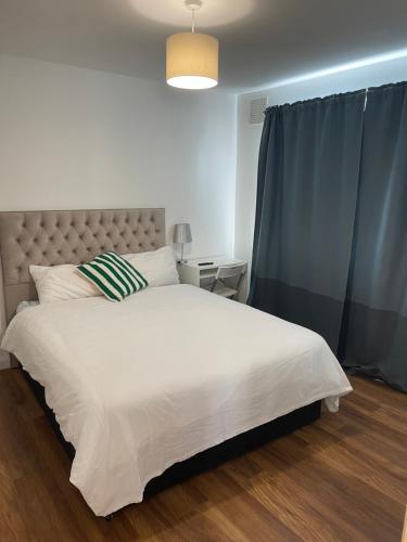 - une chambre avec un lit blanc et un rideau bleu dans l'établissement Shared house on Lakewood crescent, à Bristol
